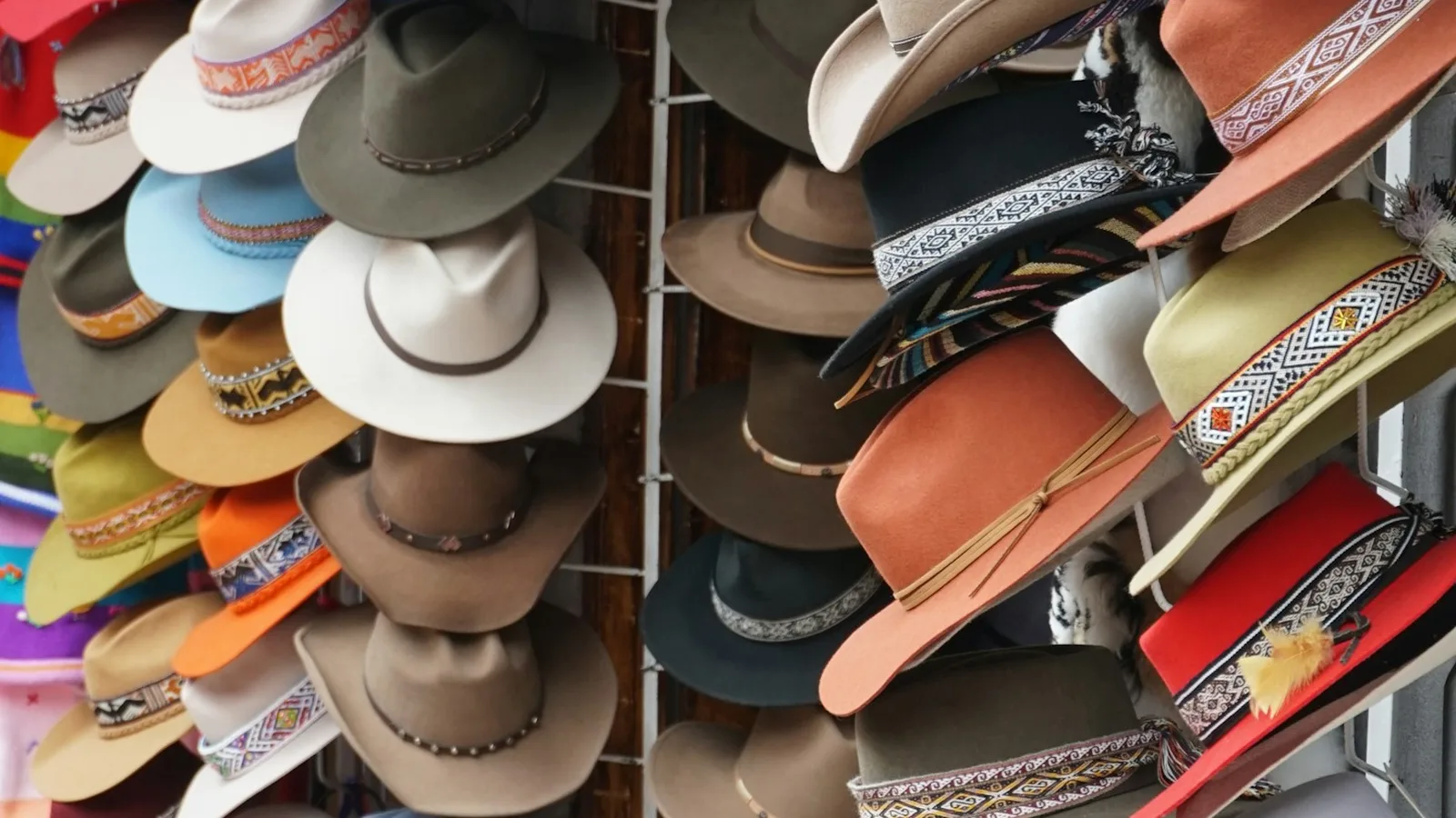 A wall of felt hats with woven bands in many colours, for sale at a market in Pisac, Peru