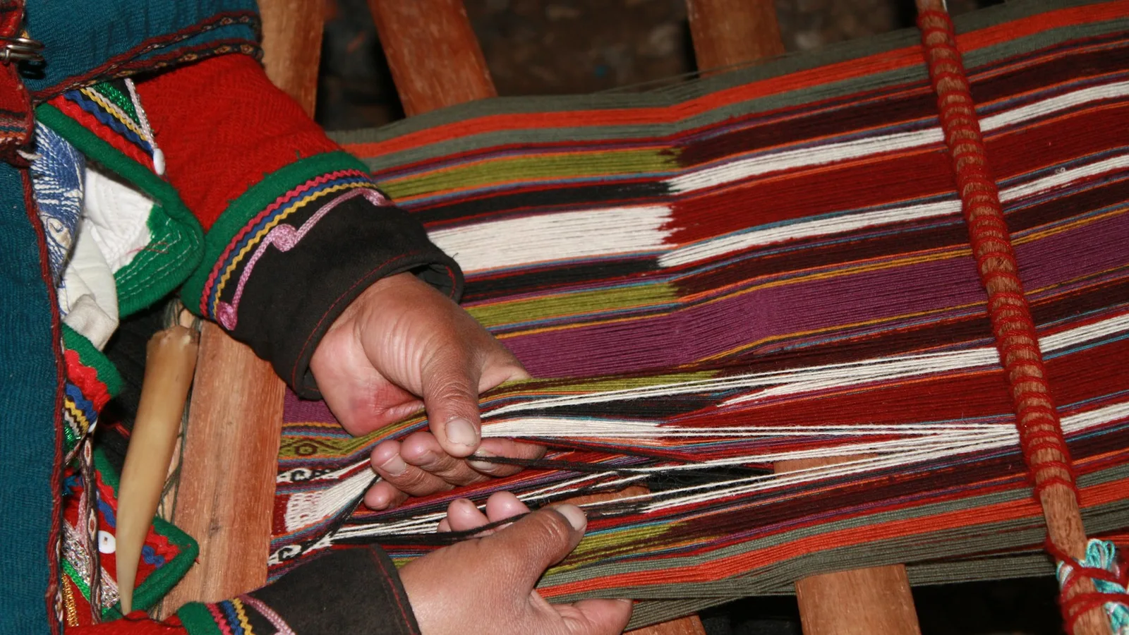Hands working colourful yarn on a traditional loom in Cusco, Peru