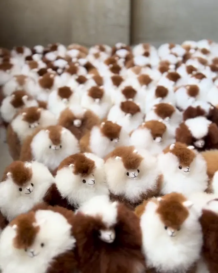 Rows of finished alpaca toys in white and brown fur, close together in the workshop