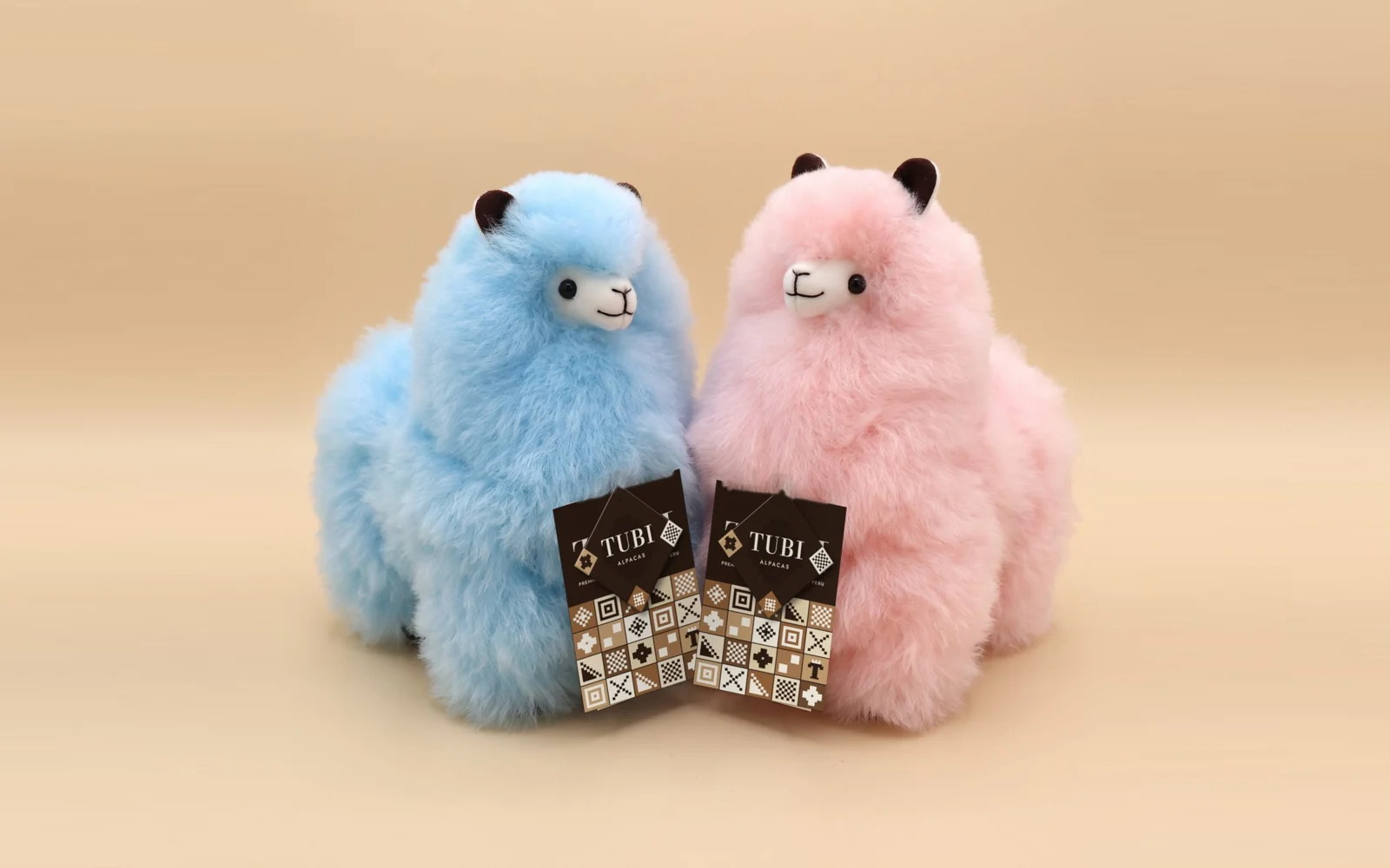 A Baby Blue and a Cotton Candy alpaca from the Rainbow collection, each with its Tubi hang tag