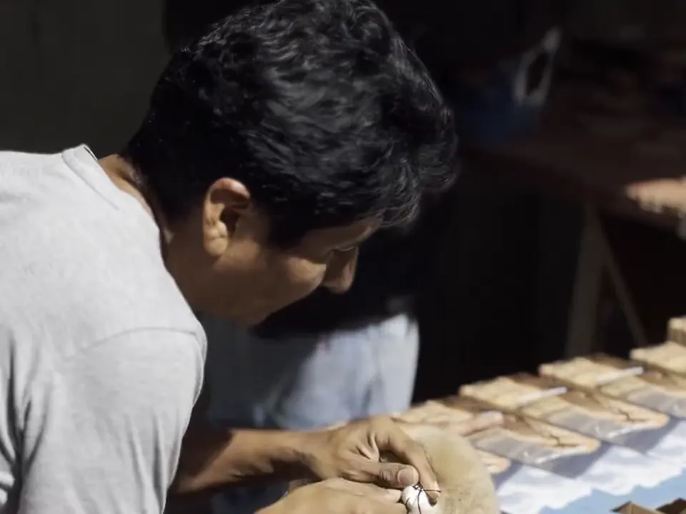 A face being stitched by hand on an alpaca toy in the Tubi workshop